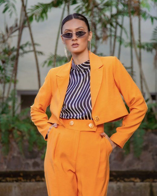 A bold orange cropped suit with a graphic striped top, an example of the Dramatic style