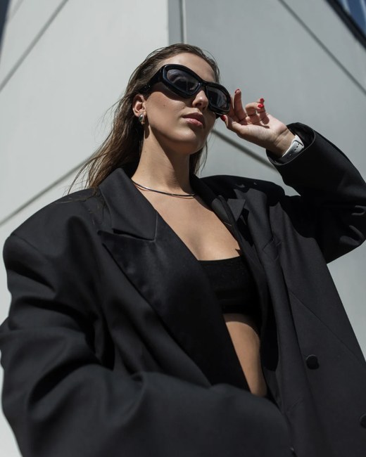 An oversized black blazer, black crop top and sculptural sunglasses, an example of the Edgy style