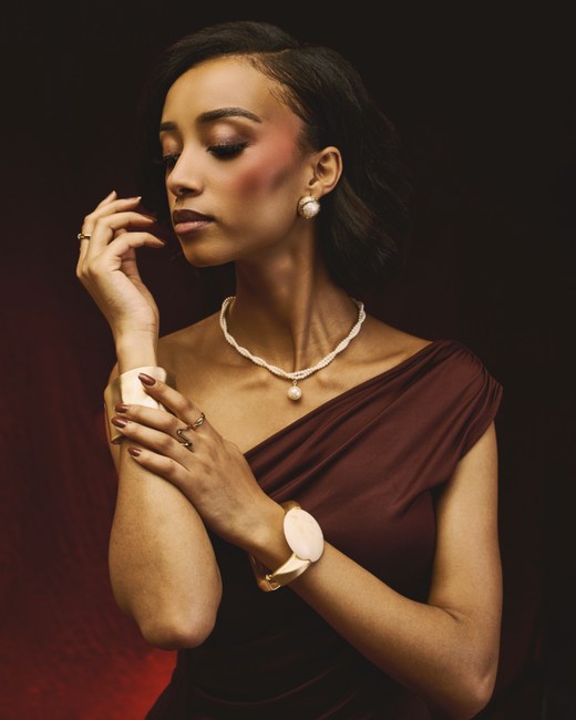 A draped wine one-shoulder dress with pearls and gold cuffs, an example of the Romantic / Elegant style