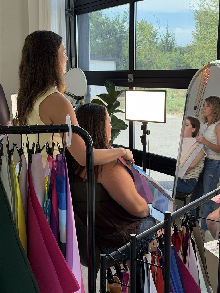 Nicole draping a guest by the windows, with drape racks in front