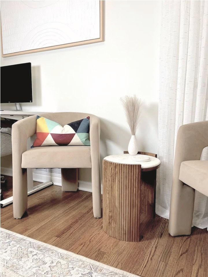 A cozy seating area with two velvet chairs and a side table